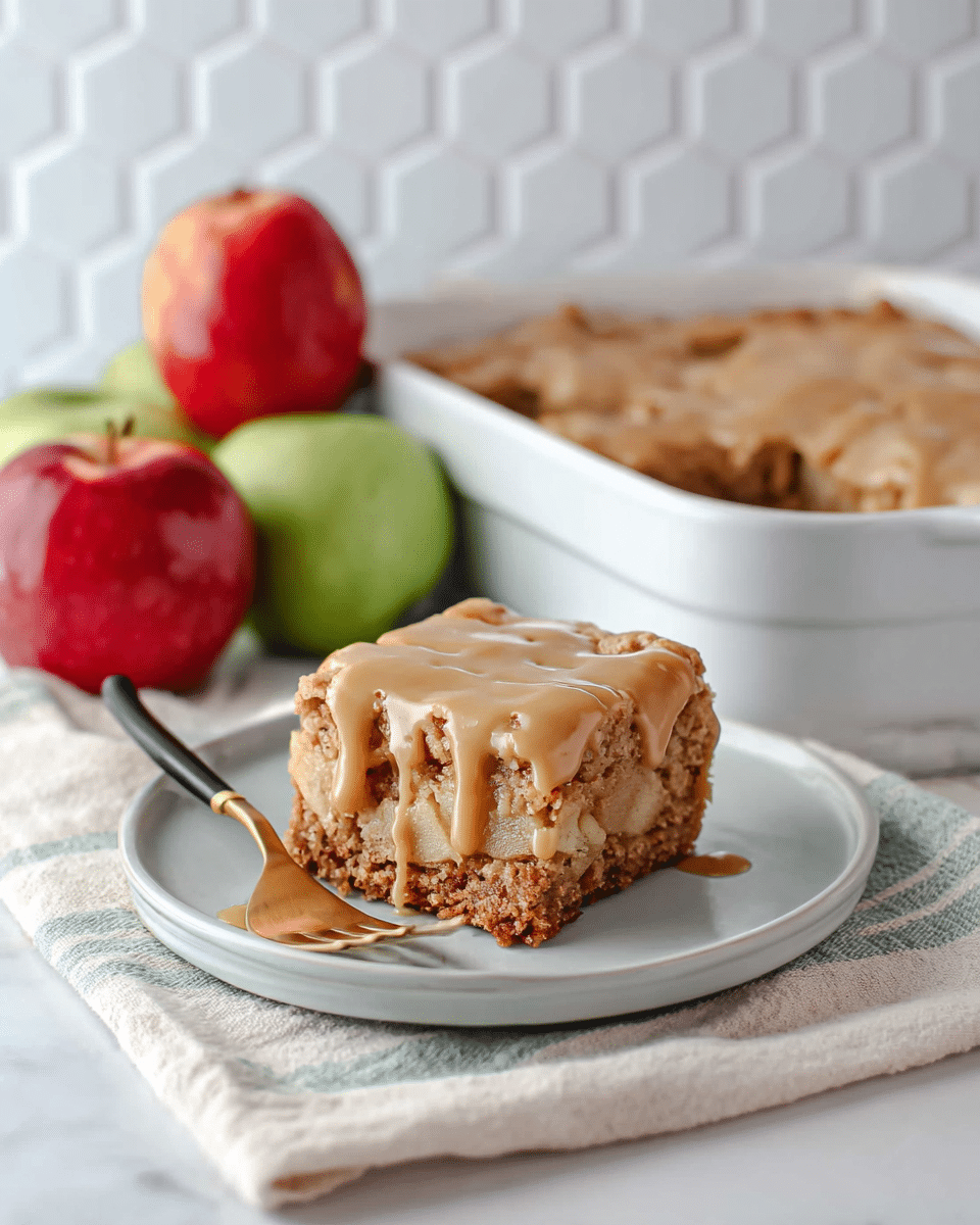 A single square piece of apple cake sits in the center of a white plate on a white marbled texture surface. The cake has two visible layers: a dense, moist, crumbly brown base filled with chunks of apple, topped generously with a thick, creamy caramel-colored glaze that slowly drips down the sides. In the background, there is a white baking dish with more apple cake and a green apple, along with a silver fork resting on the plate’s edge. The overall scene has soft lighting highlighting the texture of the moist cake and the glossy glaze. photo taken with an iphone --ar 4:5 --v 7