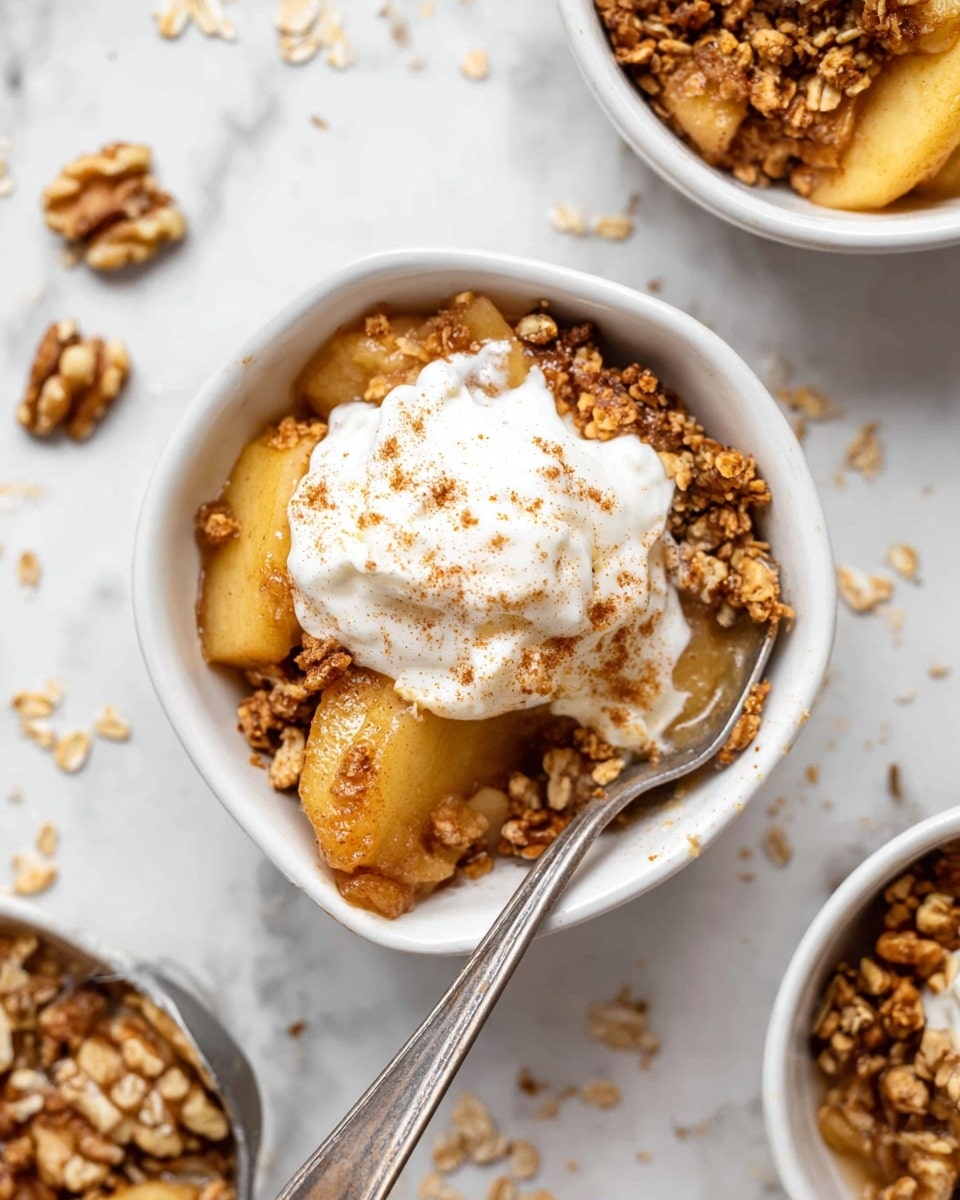 A white rectangular baking dish filled with a golden brown apple crumble that has a crumbly, oat-based topping covering sliced baked apples below; the crumble is textured with clusters of oats and small pieces of nuts. On the left side of the dish are three scoops of creamy white vanilla ice cream sprinkled lightly with cinnamon powder. A silver spoon is scooping out a portion from the bottom right corner, revealing soft, caramelized apple slices in light golden color beneath the crumb topping. The background has a white marbled texture with scattered walnut pieces and an ice cream scooper visible nearby. photo taken with an iphone --ar 4:5 --v 7
