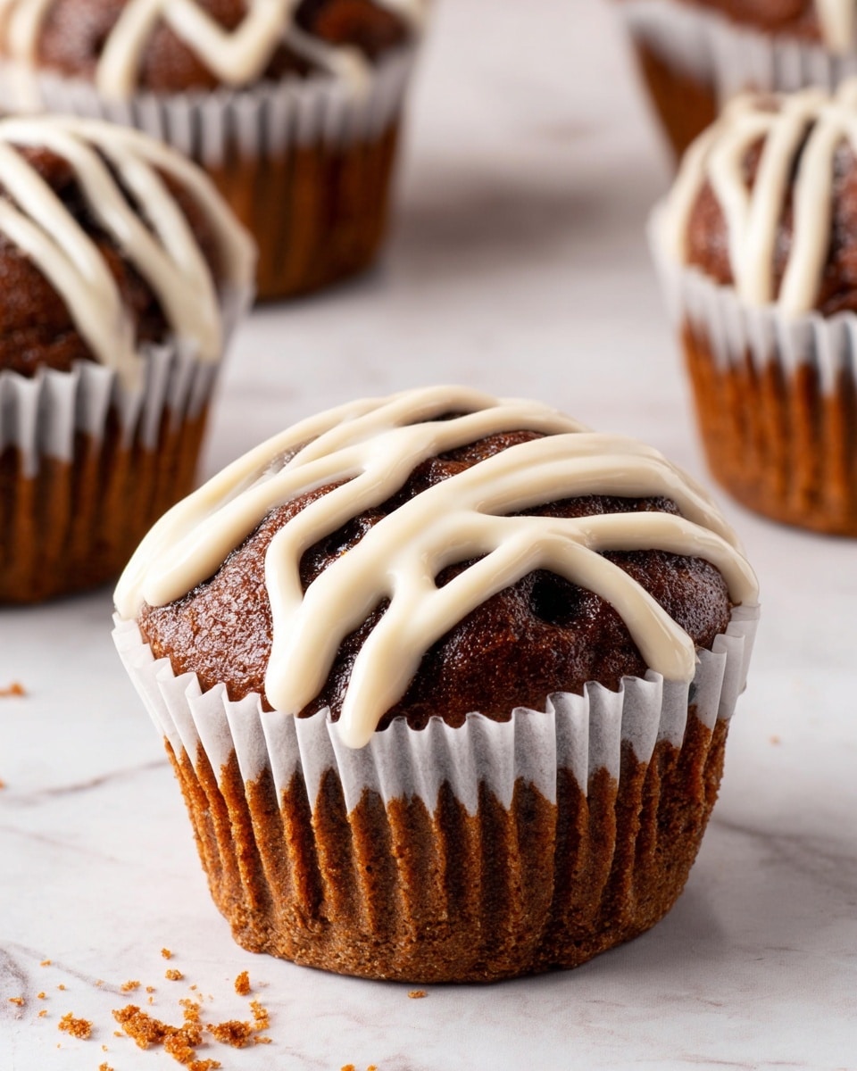 A close-up image of a single chocolate muffin with a white paper wrapper sitting on a white marbled surface, with three other muffins partially visible around it. The muffin is dark brown and rounded on top, with a thick layer of creamy white icing drizzled in a wavy pattern over the top. The texture of the muffin appears soft and moist, with some crumbs scattered lightly on the surface below. photo taken with an iphone --ar 4:5 --v 7