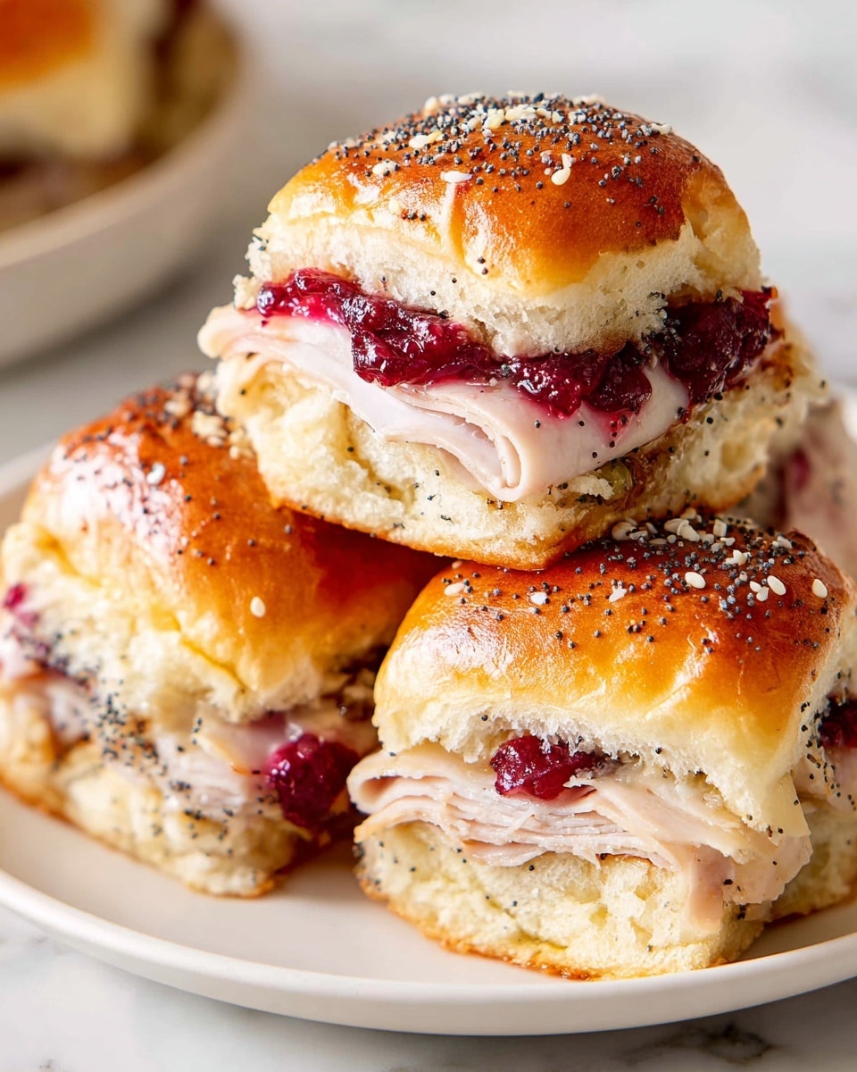 A close-up of three small sandwich sliders stacked on a white plate, each slider has a shiny golden-brown top bun sprinkled with black poppy seeds and white sesame seeds. The sliders show inside layers including a soft, slightly toasted bread base, thin slices of light pink and white turkey meat, a layer of deep red cranberry sauce, and melted, creamy white cheese that oozes slightly from the edges. The texture of the buns looks soft and fluffy with a slight crust, and the cranberry sauce adds a colorful contrast with its glossy, thick look. The plate is set on a white marbled surface. Photo taken with an iphone --ar 4:5 --v 7