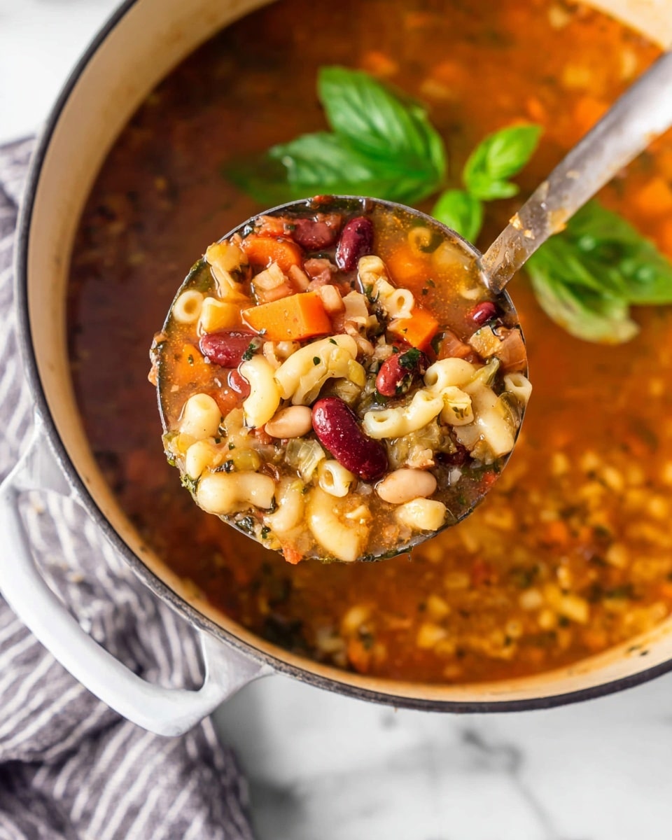 A close-up view of a ladle filled with chunky vegetable soup held above a large white pot. The soup in the ladle shows multiple layers: a base of light orange broth with visible herbs, along with layers of white beans, red kidney beans, small shell pasta, diced orange carrots, and beige potato pieces. The soup in the pot below mirrors these colors and textures with fresh green basil leaves floating on top. The pot has a glossy finish, and it sits on a white marbled surface with a gray and white striped cloth nearby. photo taken with an iphone --ar 4:5 --v 7