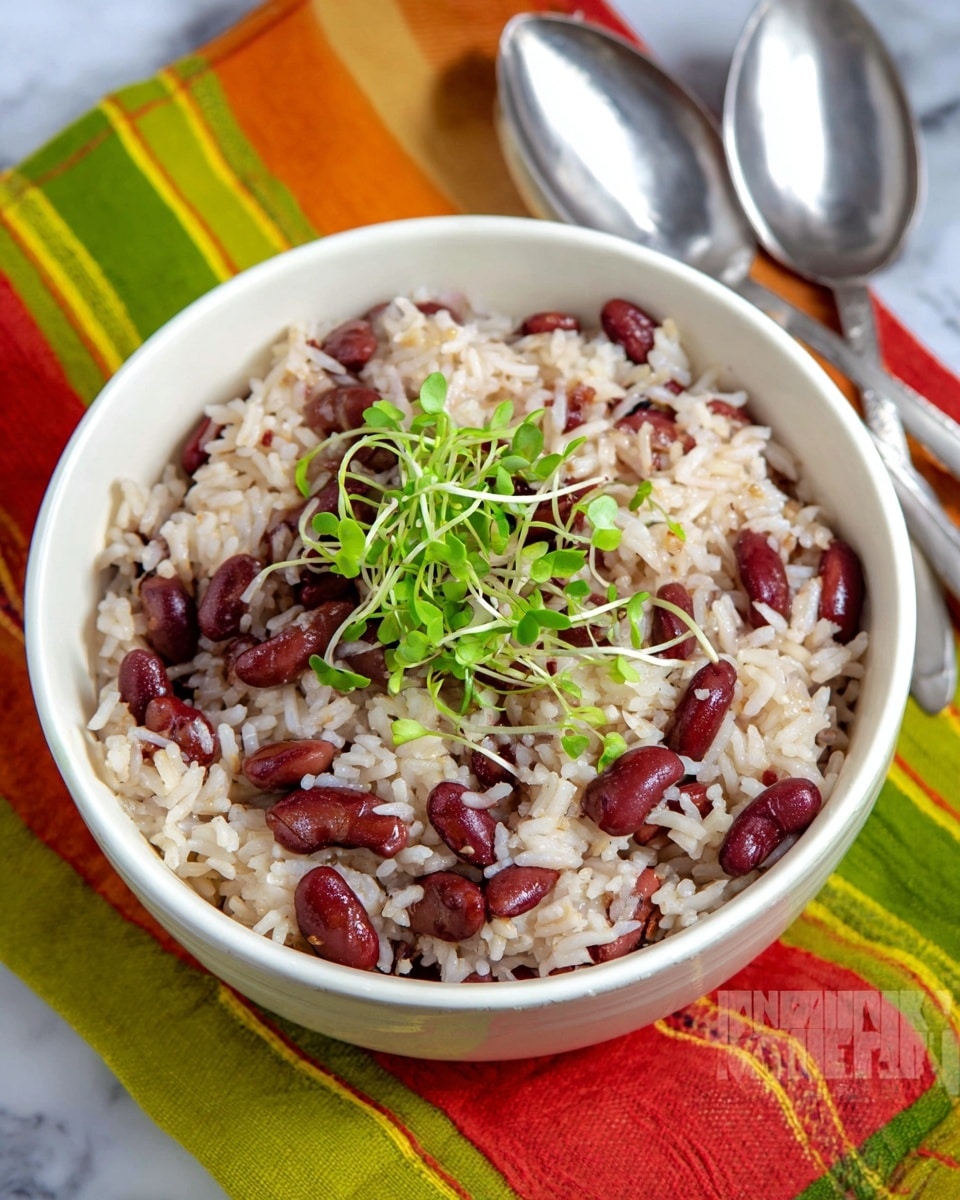A white bowl filled with a dish of cooked rice mixed with red kidney beans, creating a mix of soft white and deep red colors throughout. On top, there is a small bunch of fresh green microgreens placed in the center. The bowl rests on a colorful striped cloth with orange, green, yellow, and red stripes. Two silver spoons are placed behind the bowl, visible near the top edge of the image. The setting is arranged on a white marbled surface. Photo taken with an iphone --ar 4:5 --v 7