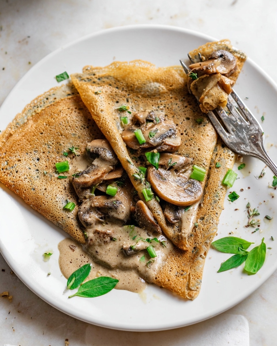 A white plate holds a thin, folded crepe with a light brown, slightly speckled texture, folded into four triangle layers covering a creamy mushroom filling. The filling has several sliced mushrooms in a light brown sauce that spills out from the center, with small pieces of green onions scattered on top. There are also green leaves of herbs like basil and cilantro on the plate’s edges. A metal fork rests on the plate with a slice of mushroom caught between its prongs on a white marbled surface. Photo taken with an iphone --ar 4:5 --v 7