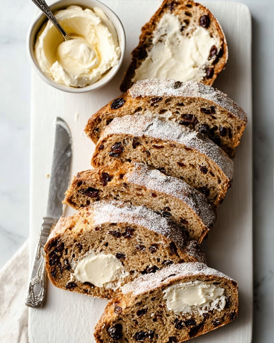 A white rectangular plate on a white marbled surface holds slices of rustic bread with a crusty, golden-brown exterior dusted lightly with flour. Each slice shows a soft, dense inside with visible bits of dark dried fruit, like raisins or cranberries. Some slices are topped with thick, creamy white spread unevenly spread across, giving a rustic and fresh look. A woman's hand holds a small butter knife above a small white bowl filled with the same creamy spread, near the top left corner of the image. Photo taken with an iphone --ar 4:5 --v 7